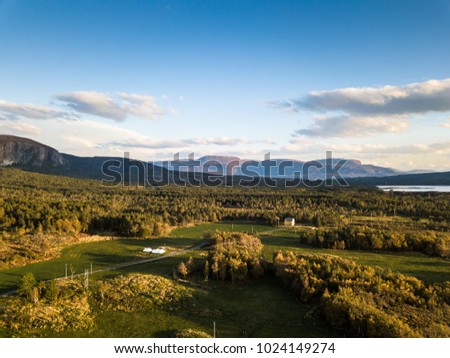 Drone Photography of a Calm Sunny Autumn Evening in Norway Countryside with Forest in the Foreground and Mountains in the Background