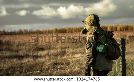 Stalker soldier in gas mask and russian military hoodie jacket looking forward while walking in the danger radioactive zone. Post apocalypse. Nuclear war. Royalty-Free Stock Photo #1024174765