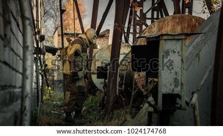 Stalker soldier in gas mask and russian military hoodie jacket walking through the industrial area in the danger radioactive zone. Post apocalypse. Nuclear war. Royalty-Free Stock Photo #1024174768