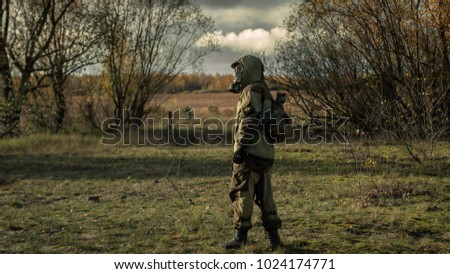 Stalker soldier in gas mask and russian military hoodie jacket looking backwards while walking in the danger radioactive zone. Post apocalypse. Nuclear war. Royalty-Free Stock Photo #1024174771