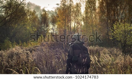 Stalker soldier in gas mask and russian military hoodie jacket looking forward while walking in the danger radioactive zone. Post apocalypse. Nuclear war. Royalty-Free Stock Photo #1024174783
