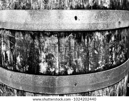 Black and white closeup of an old weathered oak barrel, showing the rough organic texture