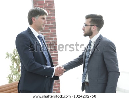 businessmen shaking hands while standing in office corridor
