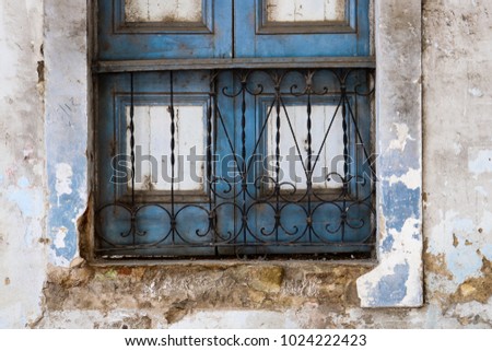 Beautiful old rustic chipped teal blue painted window with iron bars and  with distressed cracked wall border; weathered background with copy space
