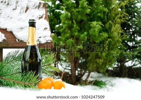 Champagne and Christmas decorations in the snow.