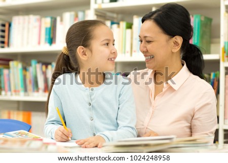 Happy mom and daughter smiling at each other while studying together at the library copyspace homework education learning childhood motherhood parenting emotions positivity lifestyle.