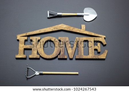 The word "home" made of wood, next to a bucket, rake, shovel