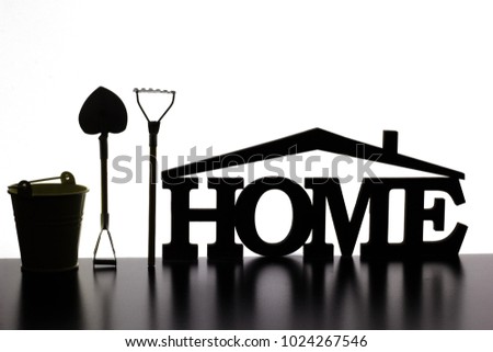 The word "home" made of wood, next to a bucket, rake, shovel