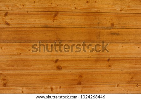 The surface of wooden boards, planks. Texture of natural wood painted with lacquer, light brown color. Close up. 