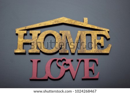 The word "love and home" is made of wood on a dark background