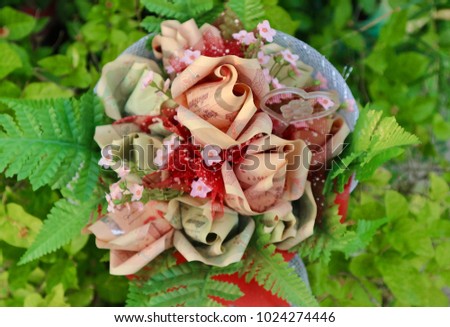 Money folded look like rose bouquet decorated with heart and little flowers in blur natural green tree