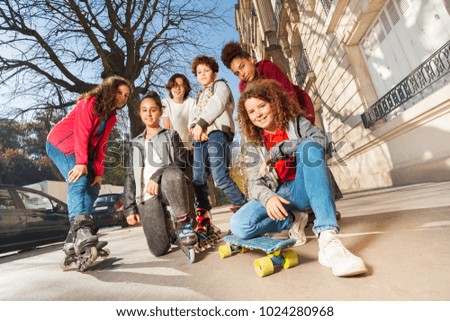 Teens with skateboard or rollerblades in cityscape