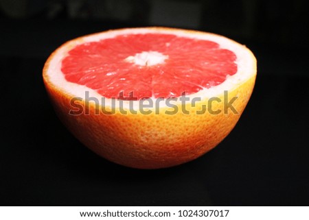 Half grapefruit on black reflective studio background. Isolated black shiny mirror mirrored background for every concept.