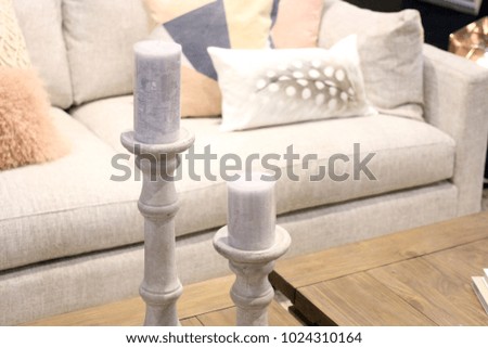 Two large church candles sitting on decorative candlesticks on a wooden coffee table.