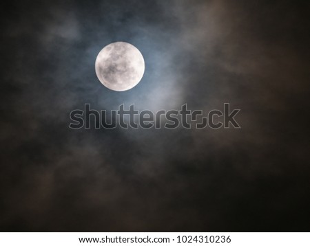 close up the detail of full moon with cloudy sky on black background , zoom image with telephoto lens