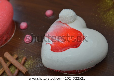 A white cake in the shape of a heart for Valentines, Anniversaries, and Birthdays. cupcakes with decorations for Valentines day