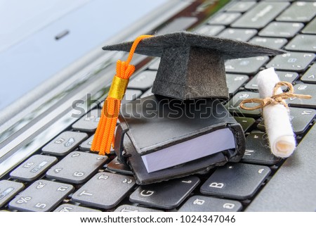 Online learning or e-learning and online graduate certificate program concept : Black graduation cap, diploma on a laptop computer keyboard, depicts distant learning can be done via cyber / internet