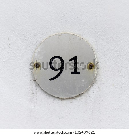 house number ninety-one on a small round plate attached with two rusty screws