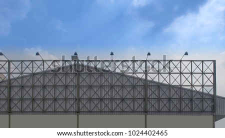 green structure steel of billboard frame with spotlights is installed in front of the factory with an aluminum sheet roof for rent on blue sky