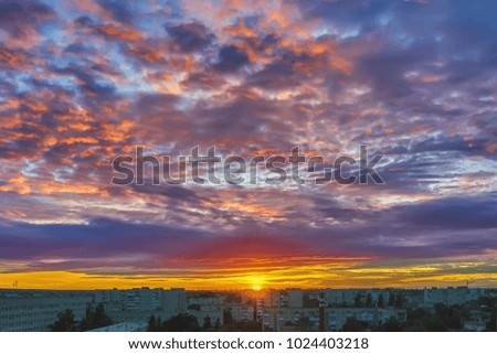 Sunrise, sky with clouds over silhouettes of houses morning city.