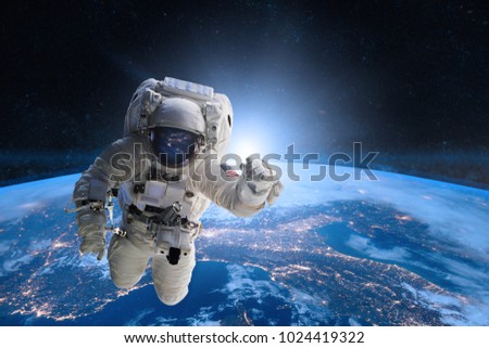 Astronaut in outer space on background of the Earth. Elements of this image furnished by NASA. Royalty-Free Stock Photo #1024419322
