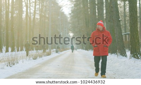 Old man is having a walk in the winter park on sunset