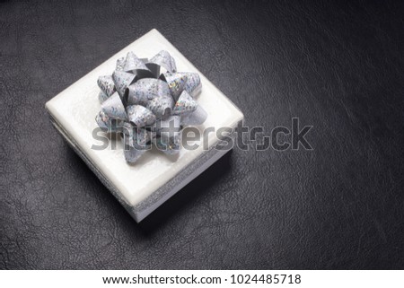 White box with a silver bow. White box on a black background