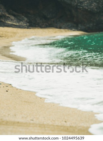 Blue sea water and sandy beach with rock at background, selective focus. Kleopatra beach, Alanya, Turkey.