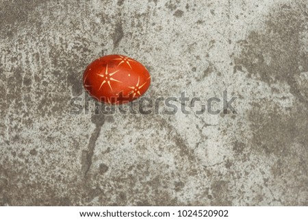 Ukrainian painted easter egg of red color on the background of a gray concrete surface