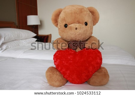 Valentines concept with teddy bear hug heart pillow on bed