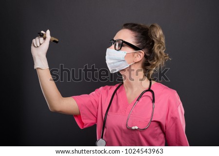 Portrait of attractive lady doctor wearing mask writing with marker on black background