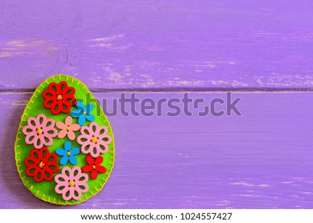 Beautiful floral Easter egg isolated on a purple wooden background with copy space for text. Felt egg crafts. Happy Easter background. Happy Easter card