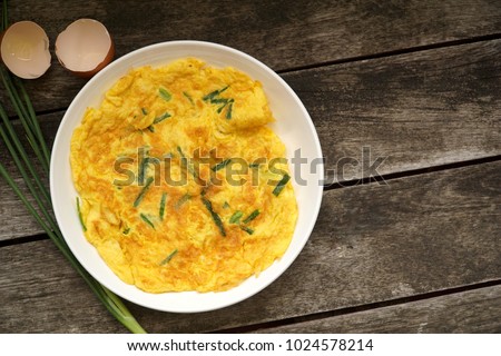 Top view of Omelet (Omelette, Scrambled) with green onion served on wood table. Fresh ingredient and put some soy sauce, sugar and pepper. Vegetarian. Still life food. Popular in Thailand. Copy space. Royalty-Free Stock Photo #1024578214