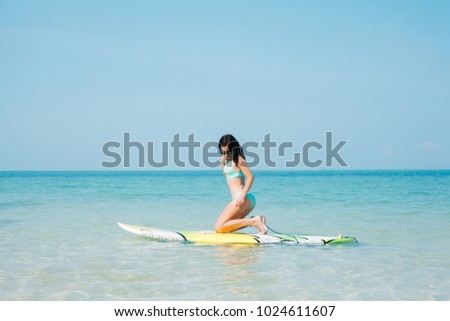 beautiful girl in bikini with paddle board on tropical beach