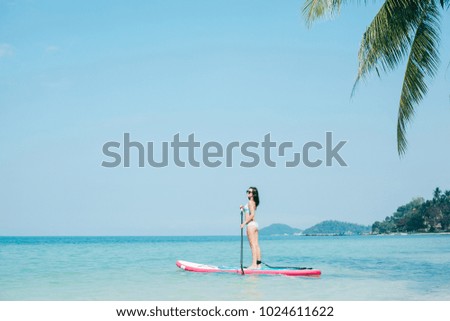 young girl on stand up paddle board on sea at tropical resort