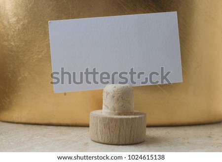 White business card with a place for writing on a stand on a gold background. place for inscription