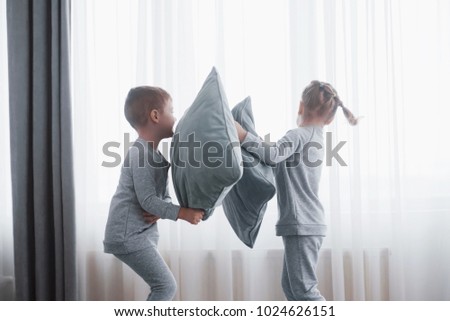 Naughty children Little boy and girl staged a pillow fight on the bed in the bedroom. They like that kind of game.