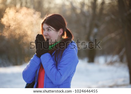 Picture of brunette warming hands in winter at woods