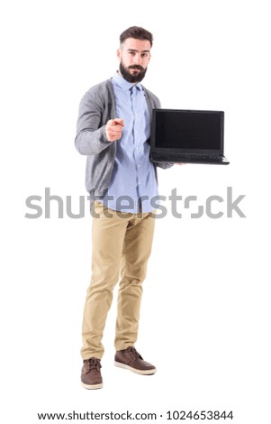 Successful confident businessman with laptop pointing finger at camera choosing you. Full body length portrait isolated on white studio background.