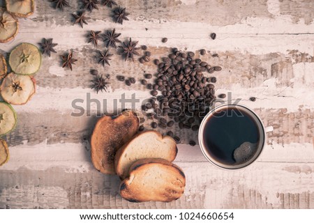 coffee cup, coffee beans of toast scattered on the rough wooden surface background