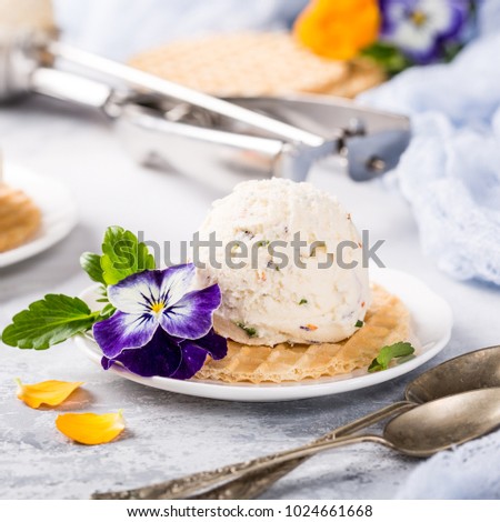 Vanilla ice cream scoop with edible flowers pansy. Summer food concept.