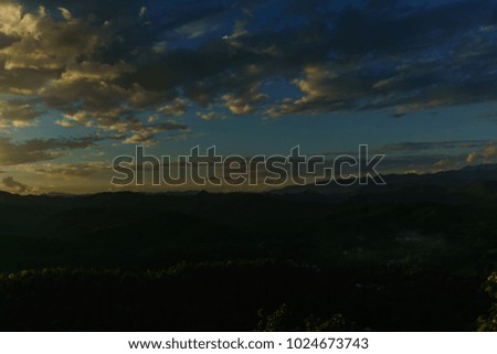 Amazing wild nature view of layer of mountain forest landscape with cloudy sky when sunset or twilight. Natural green scenery of cloud and mountain slopes background. Maehongson,Thailand