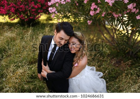 beautiful young couple bride and groom standing in the park and hugging each