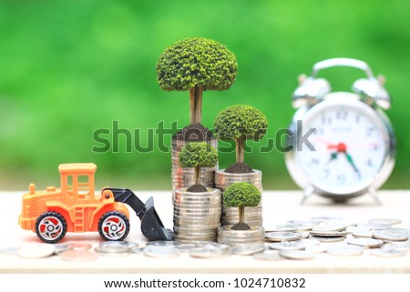 Trees growing on Stack of coins money and Truck toy on Natural green background, Real estate investments and Finance loan concept.