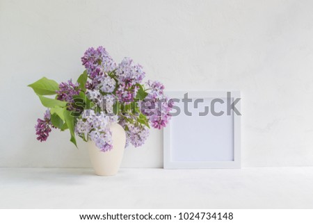 Mockup with a white frame and lilac branches in a vase on a light background