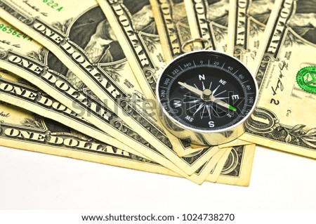 Compass laying on a pile of on dollar bills, finance and money concept