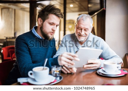 Senior father and young son with tablet in a cafe. Royalty-Free Stock Photo #1024748965