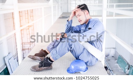 Young Asian engineers with blue helmet suffering stress fail to make mistakes in their work and business sit down on the floor at construction site. He feel very sad and serious.