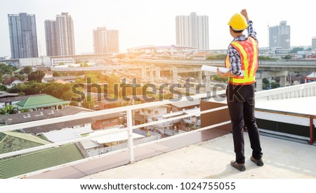 Smart engineer showing hand up and have blueprint in the hand because he happy with project successful in working area , construction building. Concept successful , engineer
