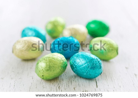 Close up of an assortment of chocolate Easter eggs on a rustic wooden background.